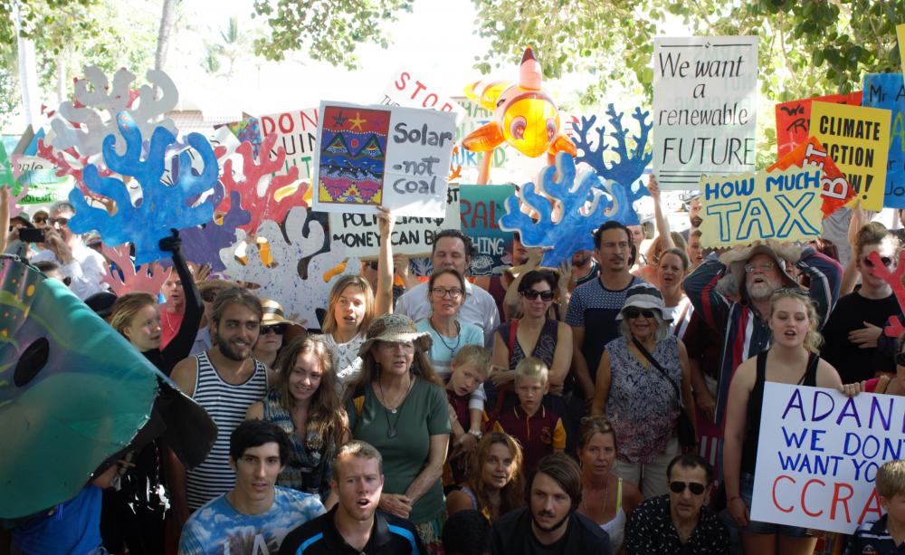 Passionate crowd of Australians at a renewable energy rally, holding signs advocating for solar power and protesting against energy taxes.