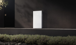 Tesla Powerwall 3P mounted on a dark exterior wall in afternoon sun